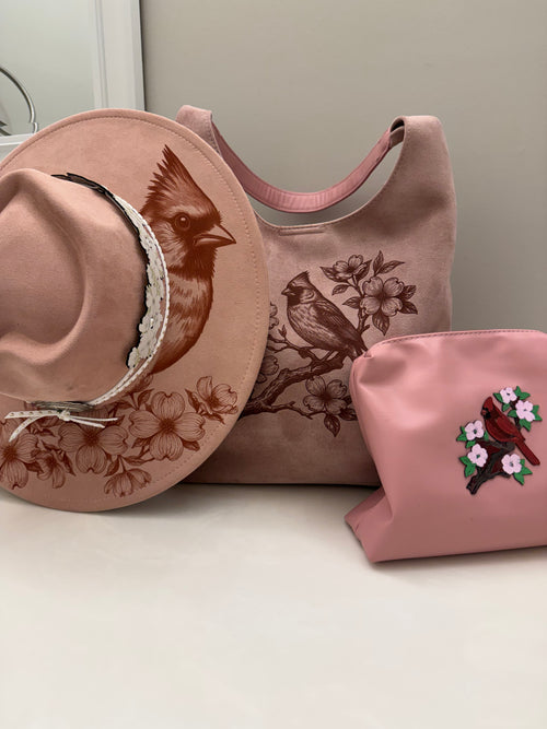 Beautiful cardinal hanging out on a branch of a Dogwood tree made by Beach Vibes NC/Crystal Coast Cowgirl Set of 3 items large brim faux suede heart shaped hat, large faux suede pink handbag and makeup bag.