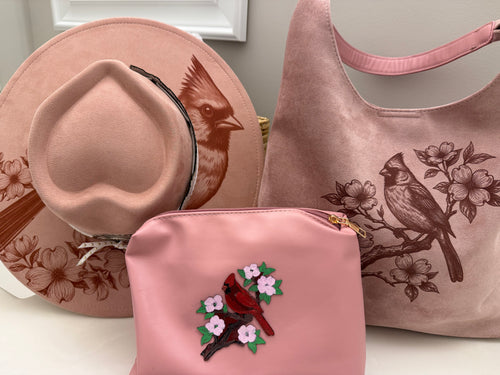 Beautiful cardinal hanging out on a branch of a Dogwood tree made by Beach Vibes NC/Crystal Coast Cowgirl Set of 3 items large brim faux suede heart shaped hat, large faux suede pink handbag and makeup bag.